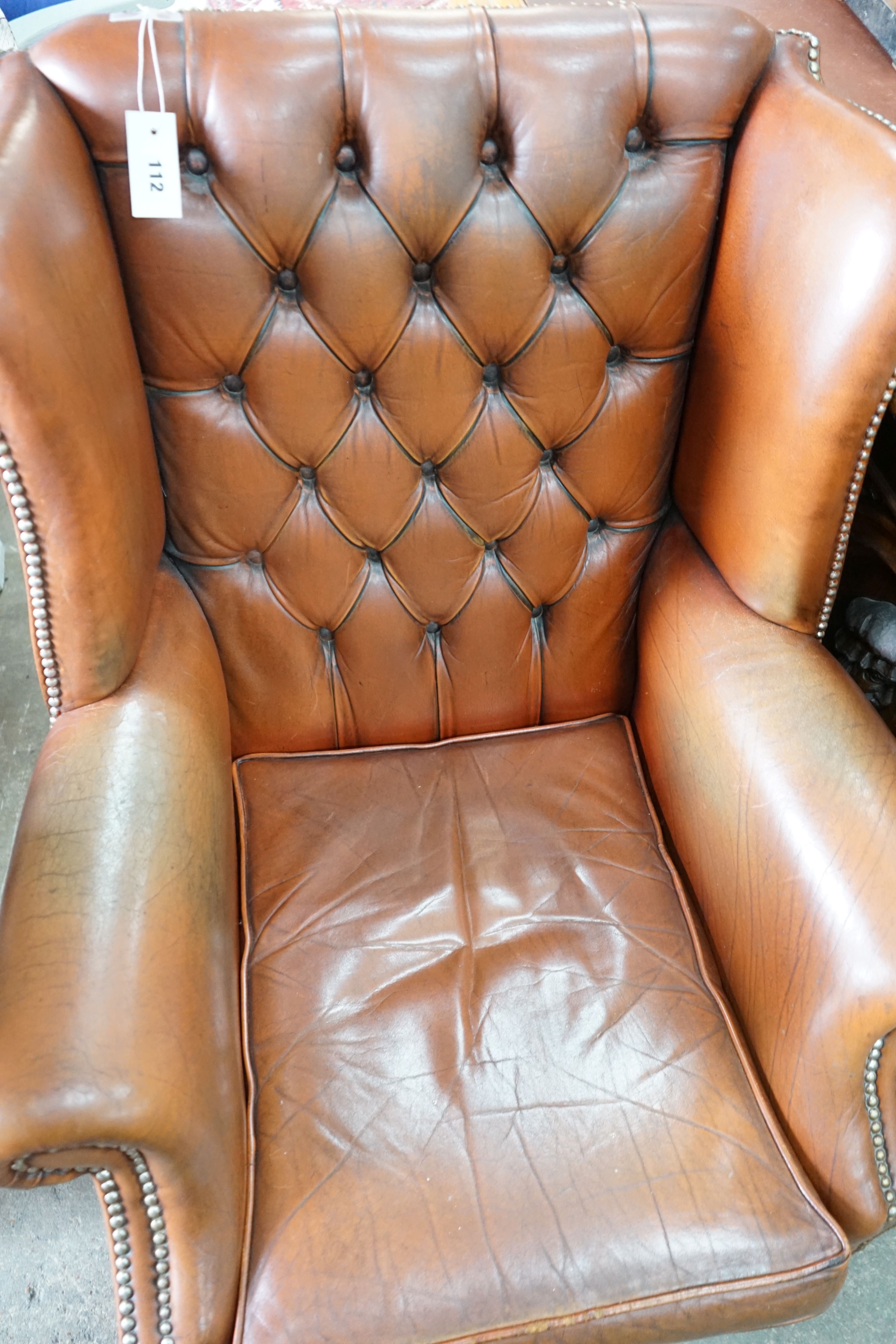 A modern buttoned brown leather wing armchair, width 70cm, depth 76cm, height 96cm